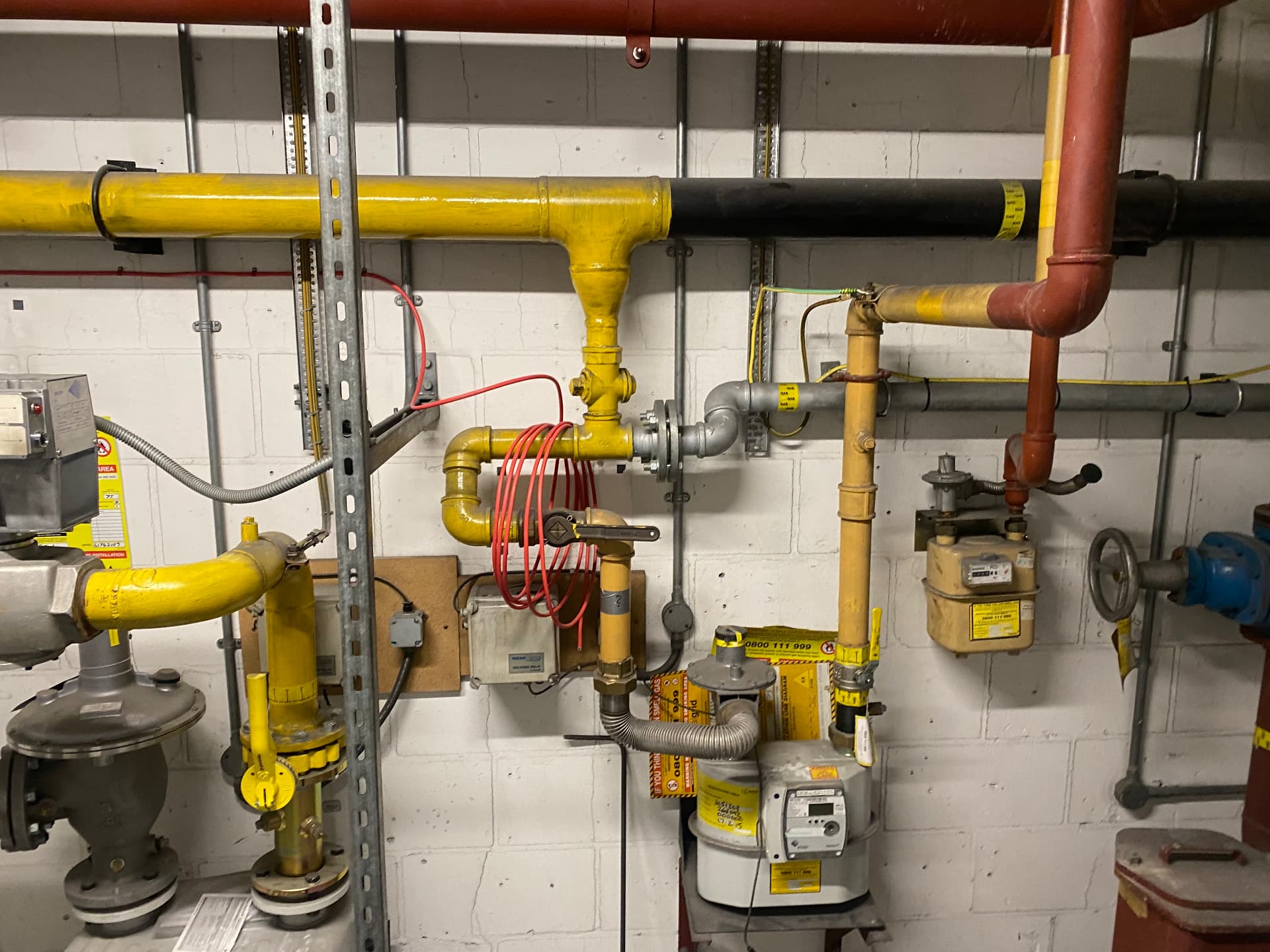 Commercial gas meter, regulator and yellow steel pipework in a plant room