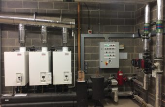 Three wall-hung commercial boilers in cascade with a control panel